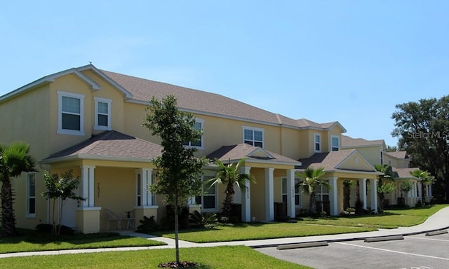 view of front of house featuring uncovered parking, a front lawn, and stucco siding