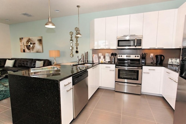 kitchen featuring visible vents, appliances with stainless steel finishes, a peninsula, white cabinetry, and a sink