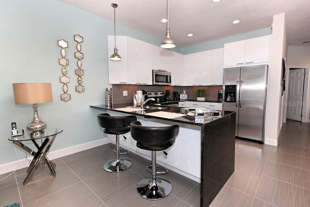 kitchen with tasteful backsplash, appliances with stainless steel finishes, a breakfast bar, hanging light fixtures, and white cabinetry