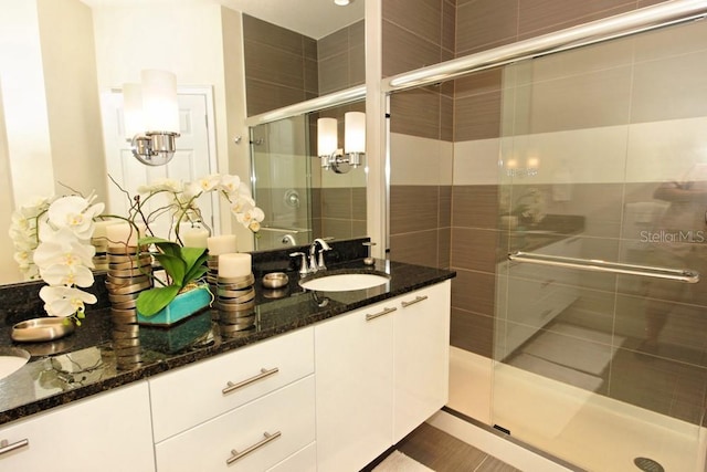 full bathroom with tile patterned flooring, a sink, a shower stall, and double vanity