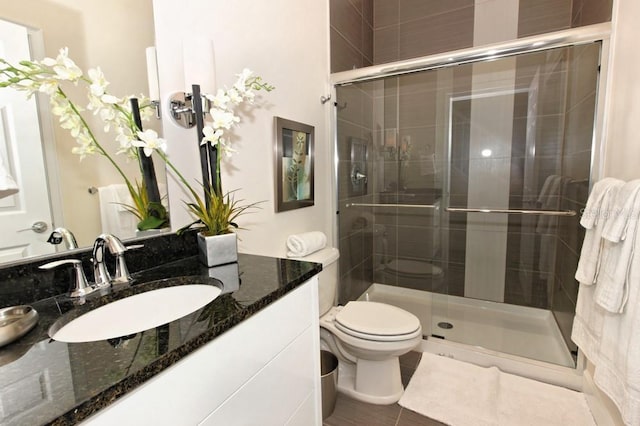 bathroom with toilet, a shower stall, vanity, and tile patterned floors