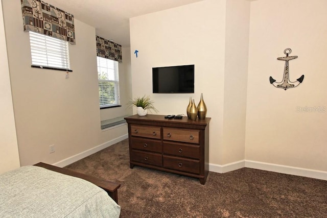 bedroom with dark carpet and baseboards