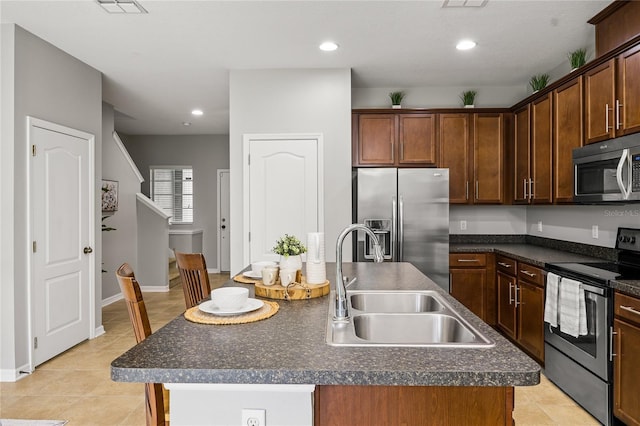 kitchen featuring appliances with stainless steel finishes, sink, an island with sink, and light tile patterned floors