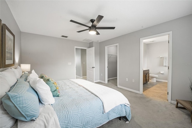 carpeted bedroom featuring ceiling fan, a walk in closet, ensuite bath, and a closet