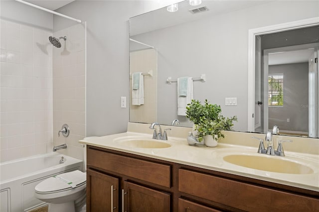 full bathroom featuring tiled shower / bath combo, vanity, and toilet