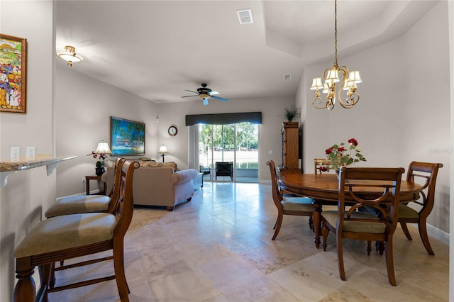 dining area with light tile patterned flooring, ceiling fan with notable chandelier, and a raised ceiling