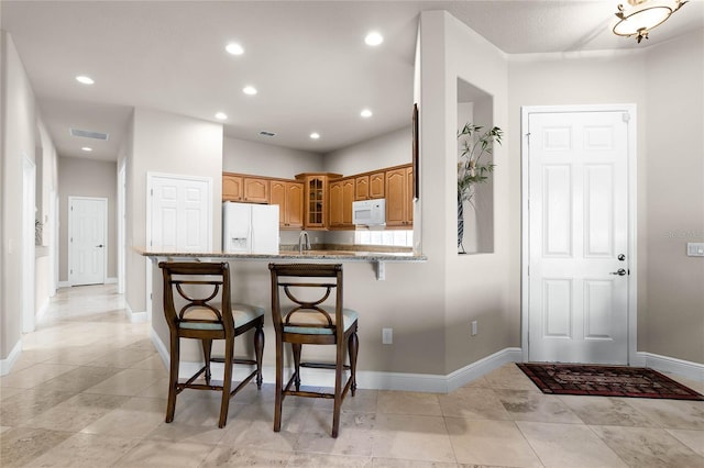 kitchen with light tile patterned flooring, kitchen peninsula, and white appliances