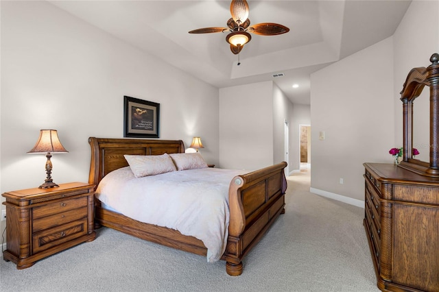 carpeted bedroom with ceiling fan and a tray ceiling