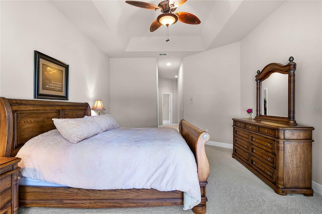 carpeted bedroom featuring ceiling fan and a raised ceiling