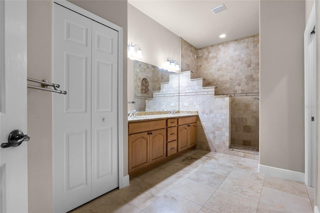 bathroom featuring dual vanity, tiled shower, and tile patterned floors