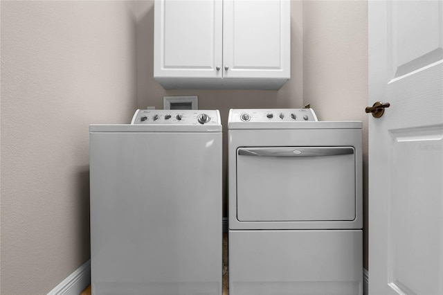 clothes washing area featuring washer and clothes dryer and cabinets