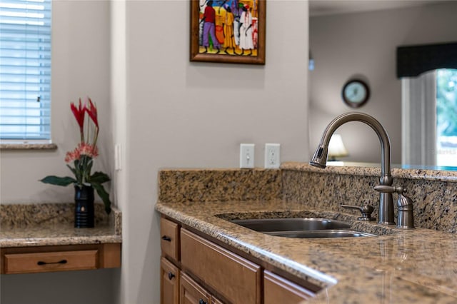 kitchen with sink, light stone countertops, and a wealth of natural light