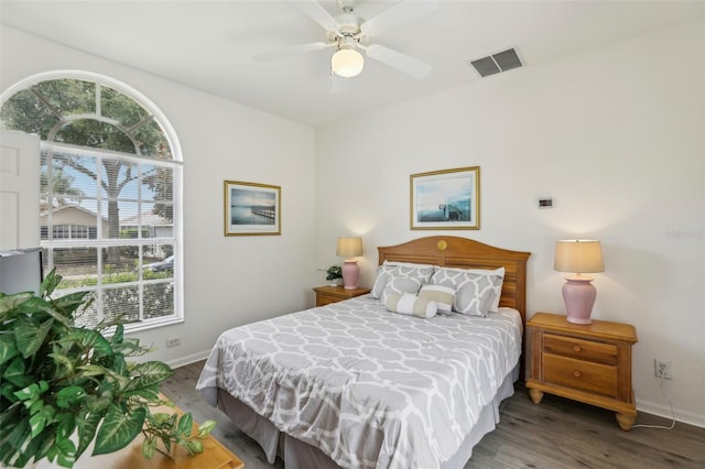 bedroom featuring multiple windows, ceiling fan, and dark hardwood / wood-style flooring