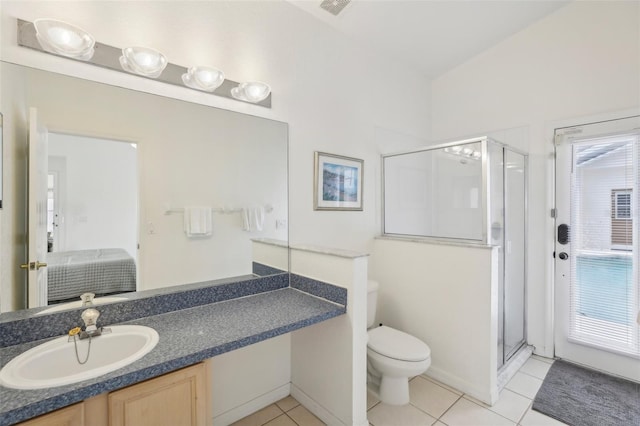 bathroom featuring tile patterned floors, toilet, vanity, a shower with door, and a healthy amount of sunlight