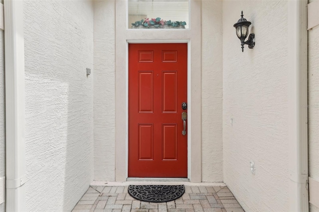 doorway to property featuring stucco siding