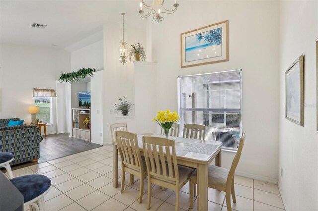 dining area featuring light tile patterned floors, baseboards, visible vents, a high ceiling, and a notable chandelier