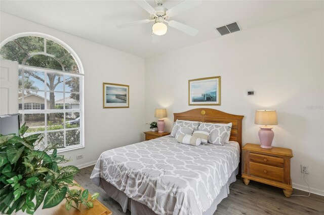 bedroom with baseboards, visible vents, multiple windows, and wood finished floors