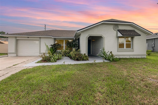 ranch-style house featuring a garage and a lawn