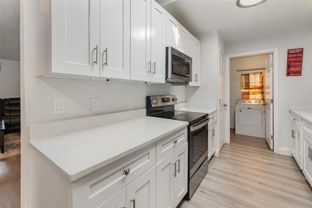 kitchen with appliances with stainless steel finishes, washer / dryer, light wood-type flooring, and white cabinets