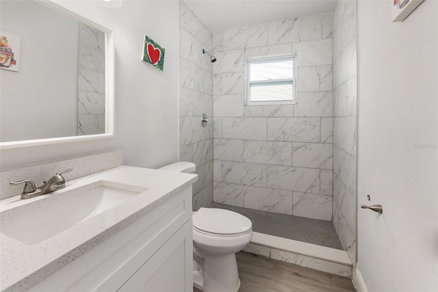 bathroom with vanity, toilet, wood-type flooring, and a tile shower