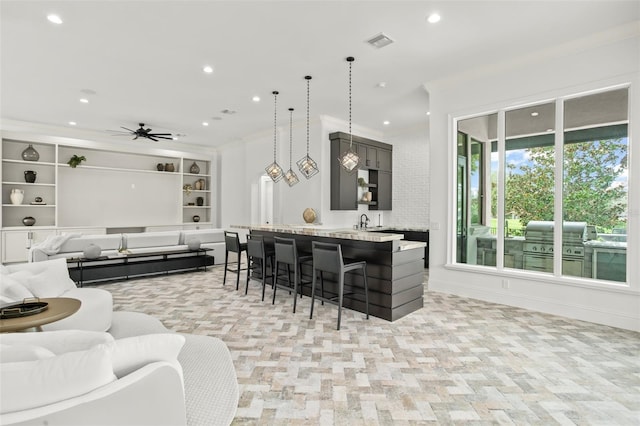 kitchen with pendant lighting, a kitchen breakfast bar, crown molding, ceiling fan, and kitchen peninsula