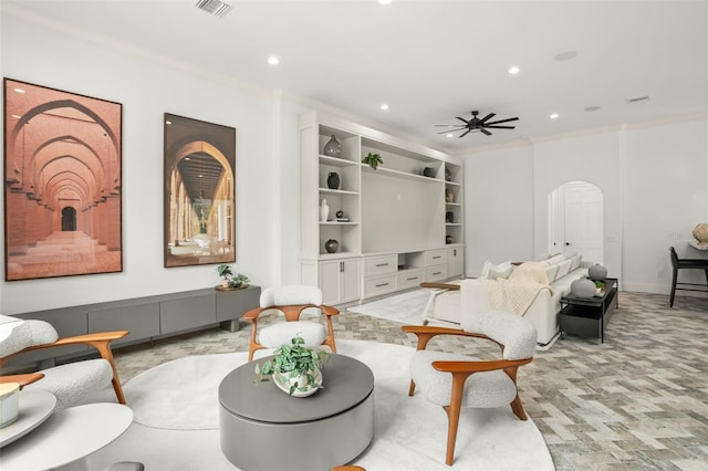 sitting room featuring built in shelves, ceiling fan, and ornamental molding