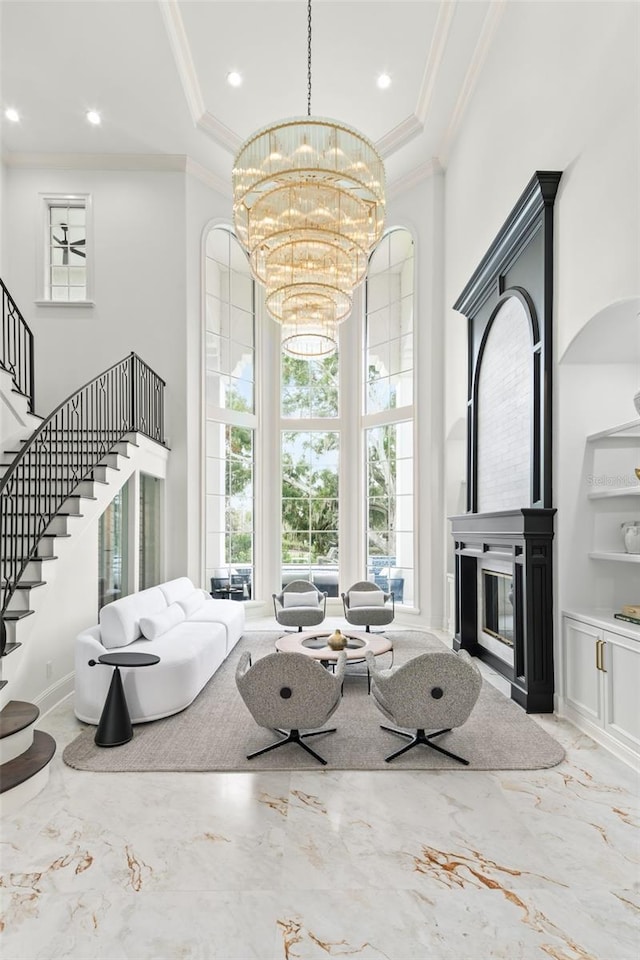 living room featuring crown molding, a chandelier, and a high ceiling