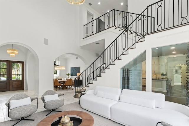 living room with a notable chandelier, a high ceiling, and french doors