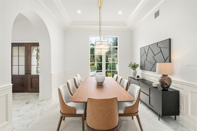 dining space with a tray ceiling, french doors, an inviting chandelier, and ornamental molding