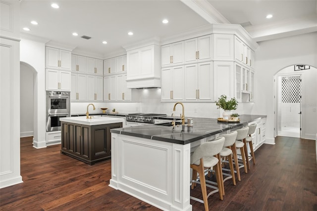 kitchen with a kitchen bar, white cabinets, sink, and an island with sink