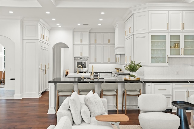 kitchen with dark hardwood / wood-style flooring, decorative backsplash, crown molding, and white cabinets