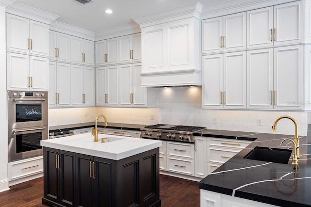 kitchen with stainless steel appliances, white cabinetry, a kitchen island with sink, and sink