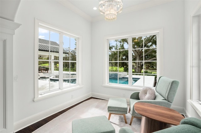 living area with hardwood / wood-style floors, an inviting chandelier, and crown molding