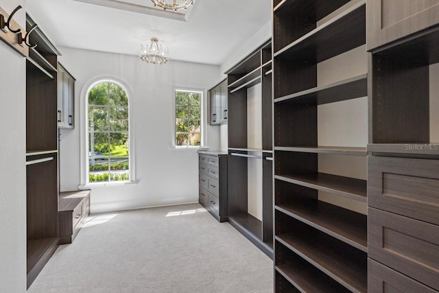 spacious closet with light carpet and an inviting chandelier