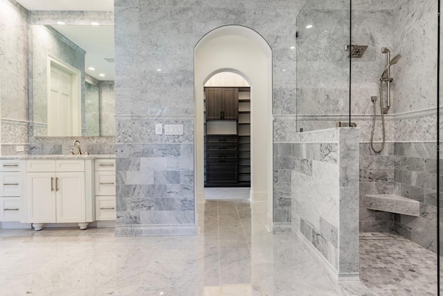 bathroom with a shower, vanity, and tile walls