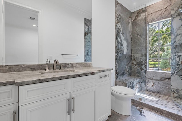 bathroom featuring vanity, toilet, a shower with door, and ornamental molding