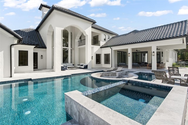 rear view of property featuring ceiling fan, a swimming pool with hot tub, and a patio