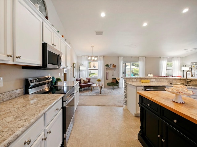 kitchen featuring sink, white cabinetry, decorative light fixtures, light wood-type flooring, and stainless steel appliances