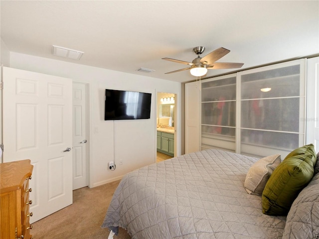 bedroom with light carpet, ensuite bath, and ceiling fan