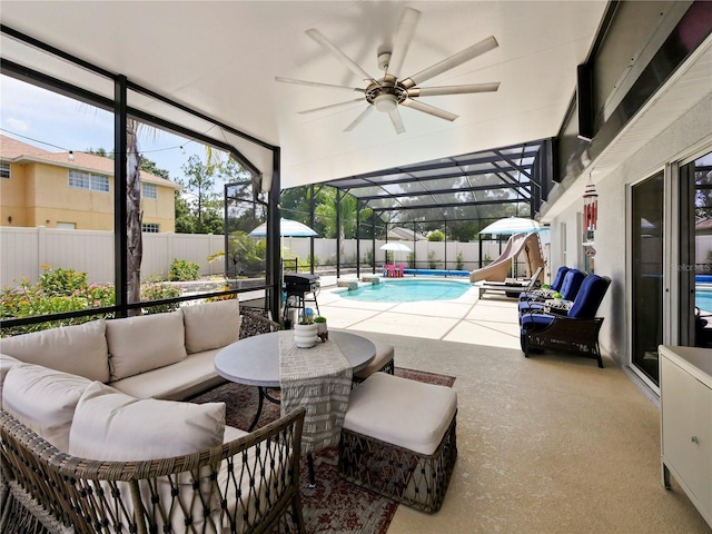 view of pool with an outdoor living space, a patio area, glass enclosure, and a water slide