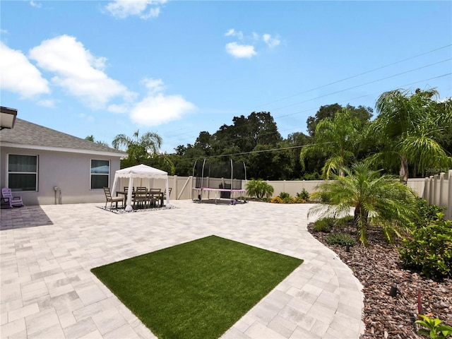 view of yard with a trampoline and a patio