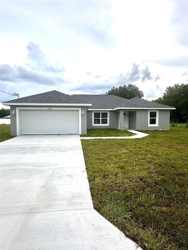 ranch-style house featuring driveway, a shingled roof, an attached garage, a front lawn, and stucco siding