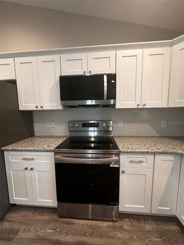 kitchen with lofted ceiling, stainless steel appliances, light stone countertops, and white cabinets