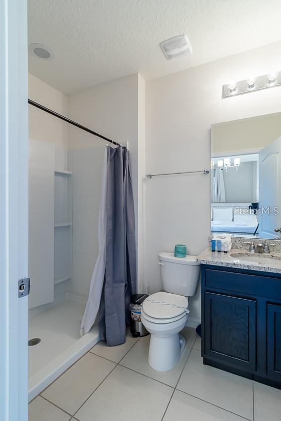 bathroom with vanity, tile patterned flooring, curtained shower, and a textured ceiling