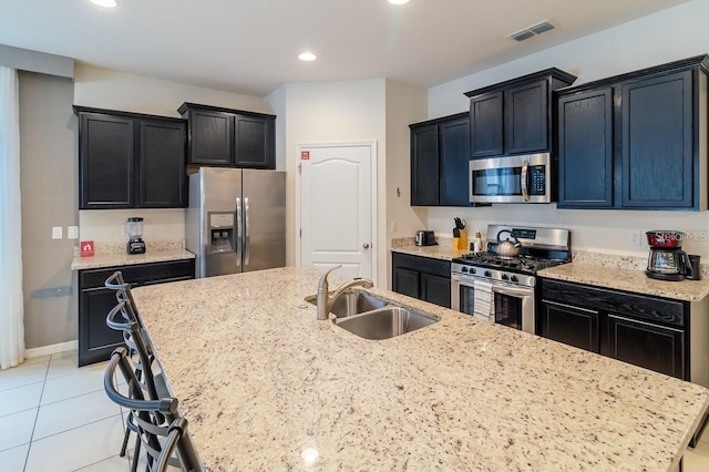 kitchen featuring appliances with stainless steel finishes, sink, and light stone counters