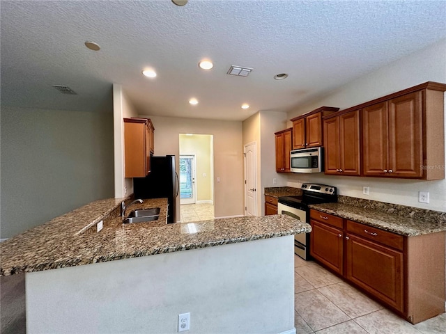 kitchen featuring light tile patterned floors, sink, appliances with stainless steel finishes, a textured ceiling, and kitchen peninsula