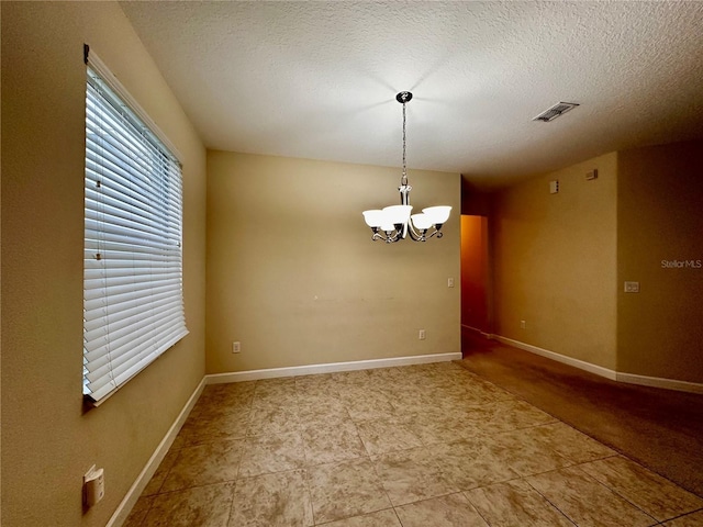 empty room with a textured ceiling and an inviting chandelier