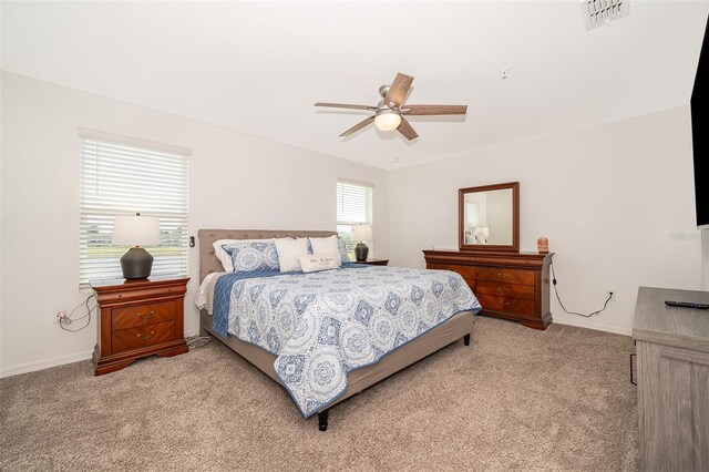 bedroom featuring multiple windows, ceiling fan, and light colored carpet