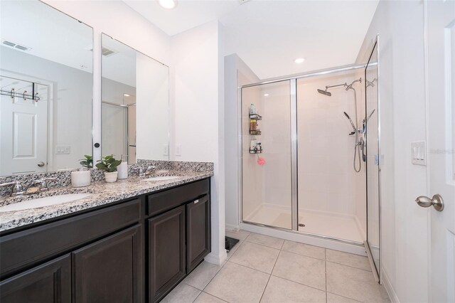 bathroom with tile patterned floors, a shower with door, and double vanity