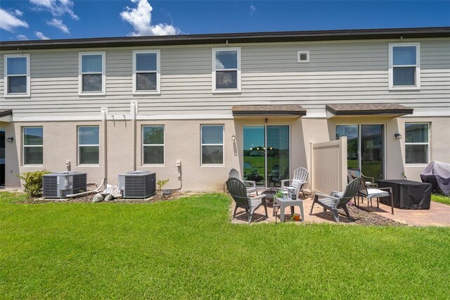 rear view of property with cooling unit, a lawn, and a patio area